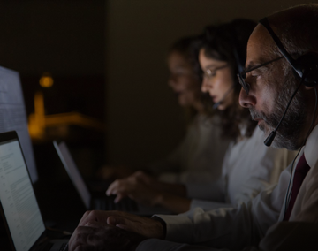 Atendentes com headset em um ambiente de call center, focados em seus computadores