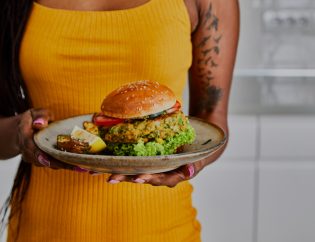 Mulher segurando um prato de hamburguer vegano