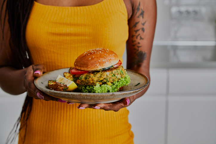 Mulher segurando um prato de hamburguer vegano