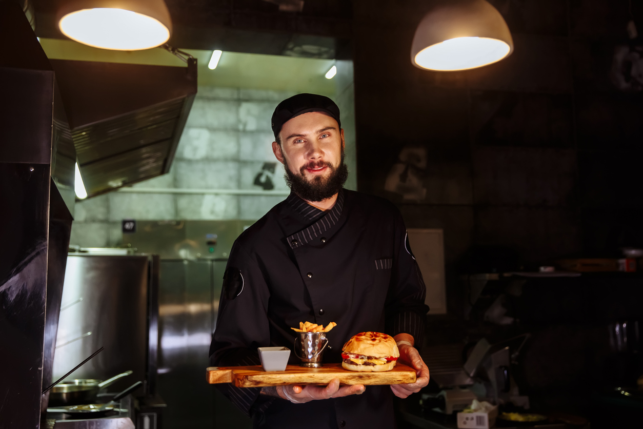 Chef com um combo de hambúrguer e batata frita nas mãos